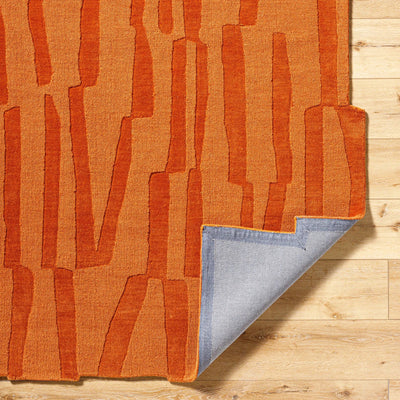 Livabliss Mystique M-5488 Burnt sienna hand-loomed wool area rug with abstract texture, corner folded to show grey backing on wood floor.