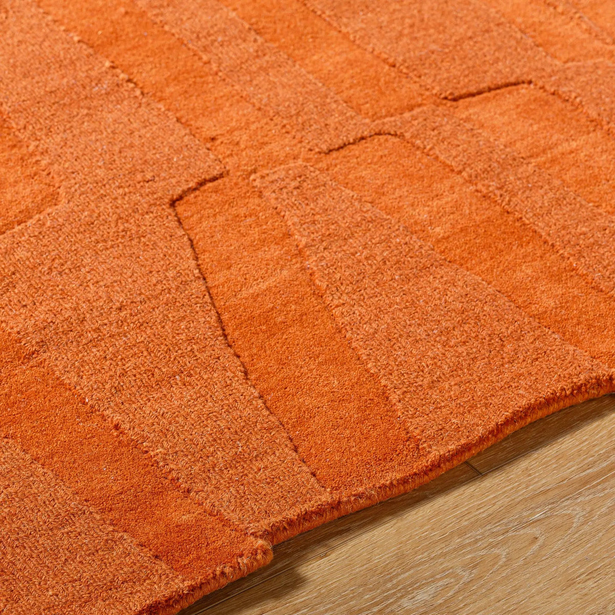 Livabliss Mystique M-5488 Burnt sienna wool area rug featuring a textured geometric pattern and medium pile, resting on light wood flooring.