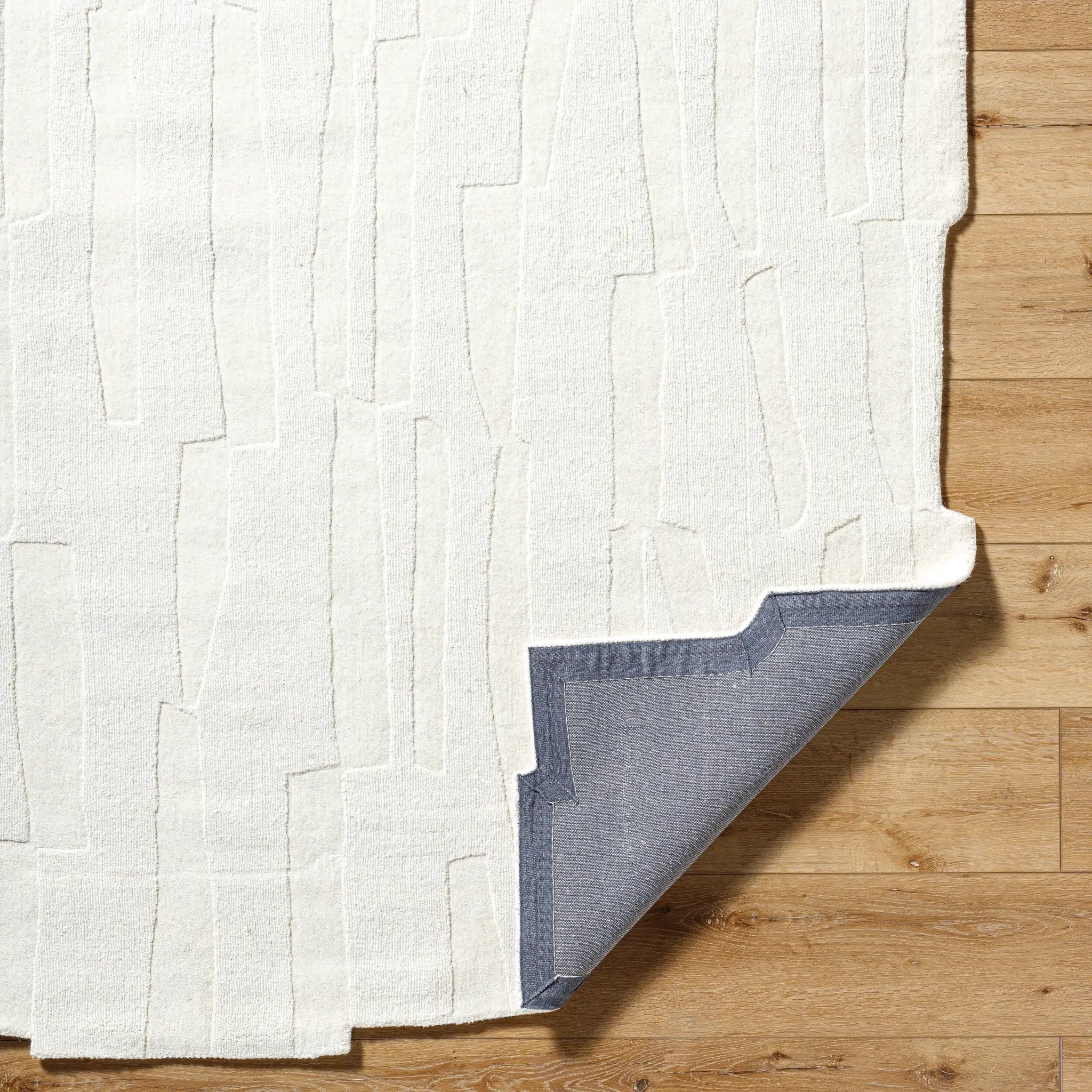 Livabliss Mystique M-5489 Ivory area rug with textured geometric wool pattern and blue backing. Hand-loomed neutral design for living spaces.
