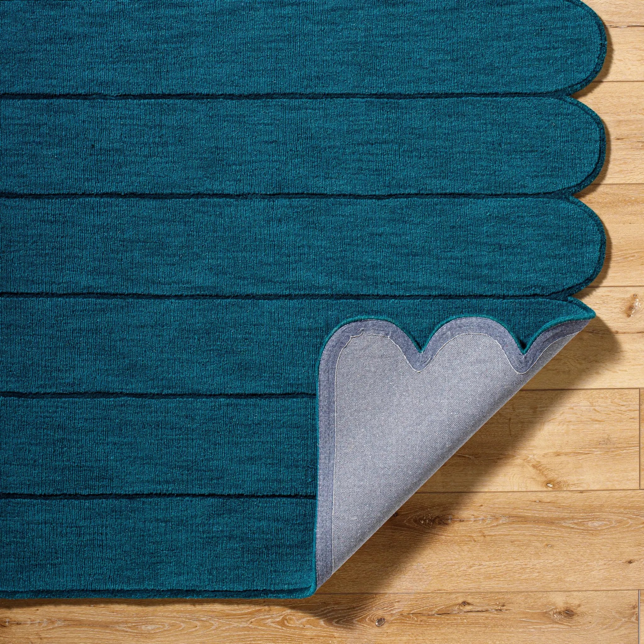 Livabliss Hand Loomed Mystique M-5491 Teal area rug with horizontal striations and scalloped edges. Medium-pile wool texture with corner lifted to show grey backing on wood floor.