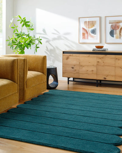 Livabliss Mystique M-5491 Teal hand-loomed wool area rug with distinctive ribbed texture placed on hardwood floors beside a mustard armchair and wooden sideboard.