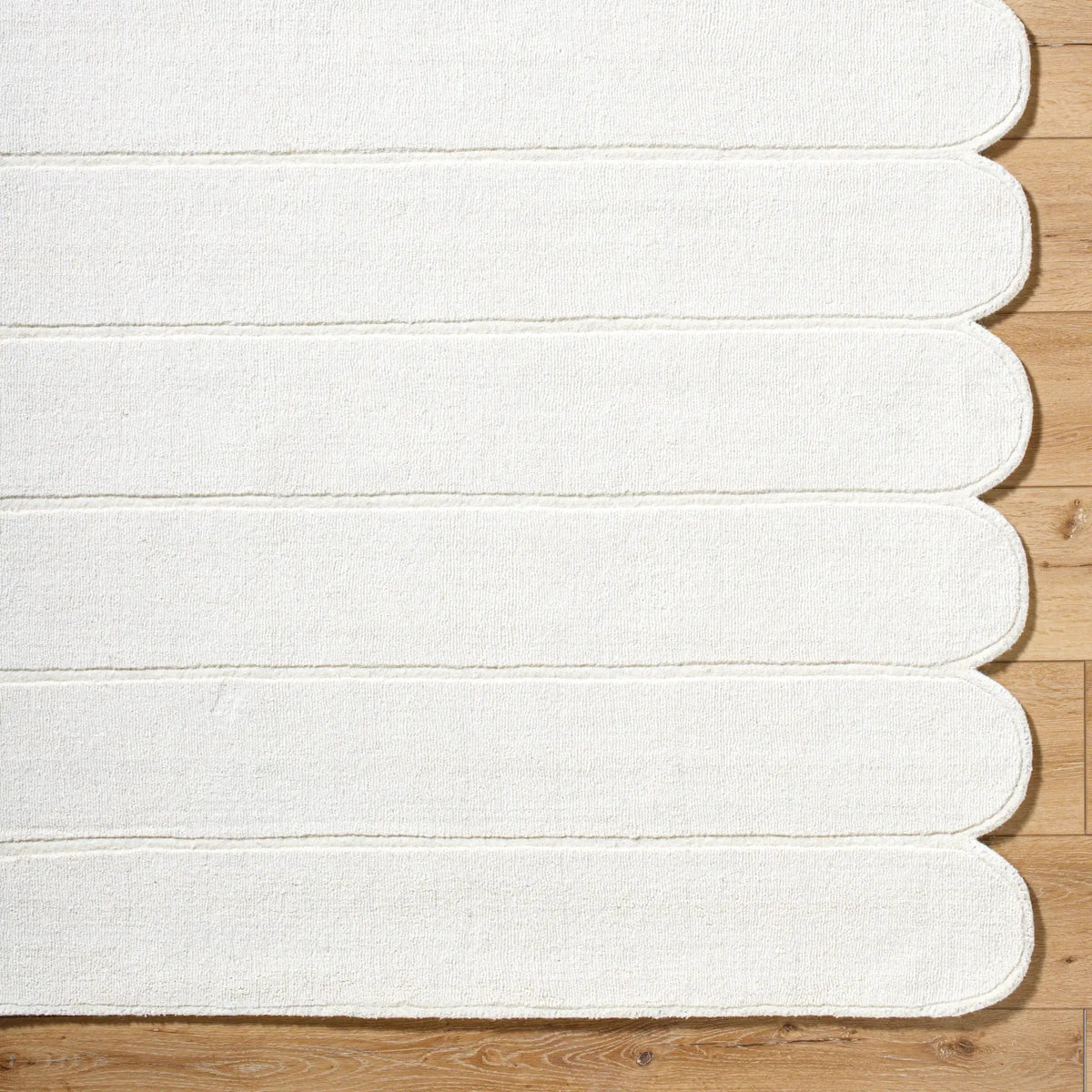 Livabliss Mystique M-5492 Ivory hand-loomed wool area rug with striped texture and scalloped edge lying on light wood flooring.