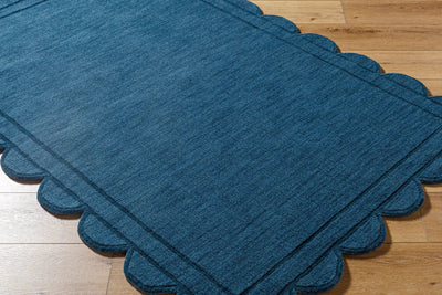 Livabliss Mystique M-5493 Indigo hand loomed wool area rug with scalloped edges and textured weave resting on light hardwood flooring.