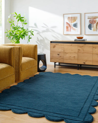Hand loomed Livabliss Mystique M-5493 indigo wool area rug with scalloped edges adds texture to a modern living room featuring mustard seating and natural wood accents.