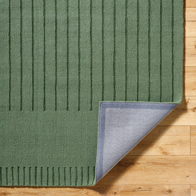 Livabliss Mystique M-5495 Sage green wool hand loomed area rug with textured vertical stripes and grey backing corner lifted on hardwood floor.