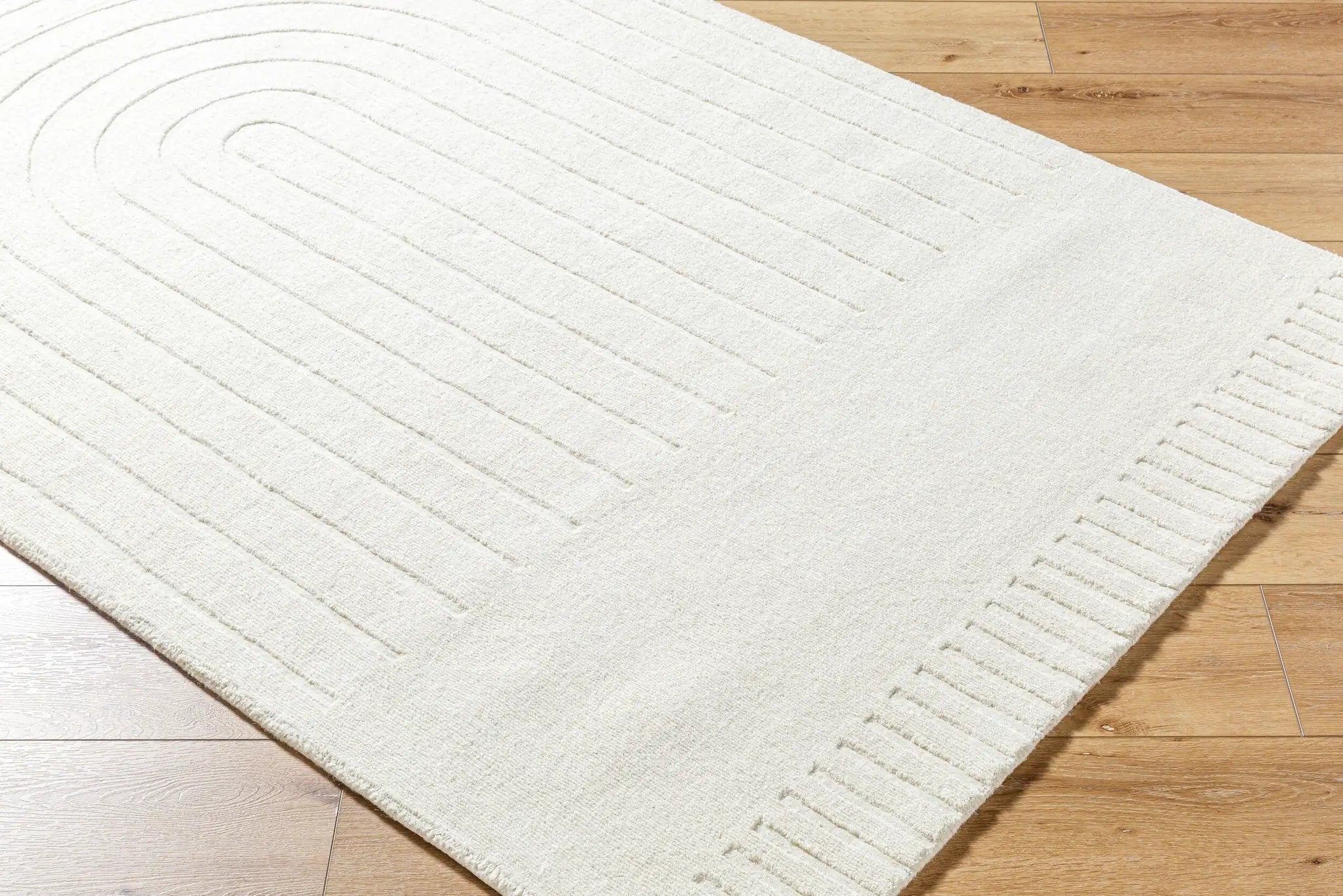 Textured Livabliss Mystique M-5496 ivory wool area rug with curved carved lines and ribbed border, handmade in India for versatile living room or bedroom decor.