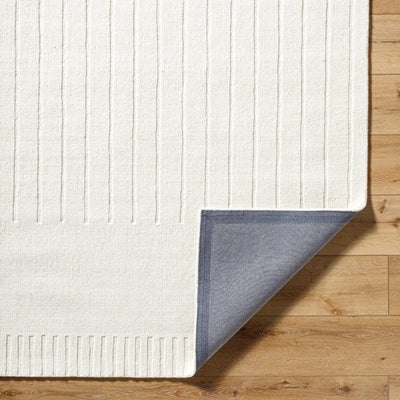 Livabliss Mystique M-5496 Ivory hand-loomed wool ribbed area rug, corner lifted to reveal grey backing, resting on light hardwood flooring.