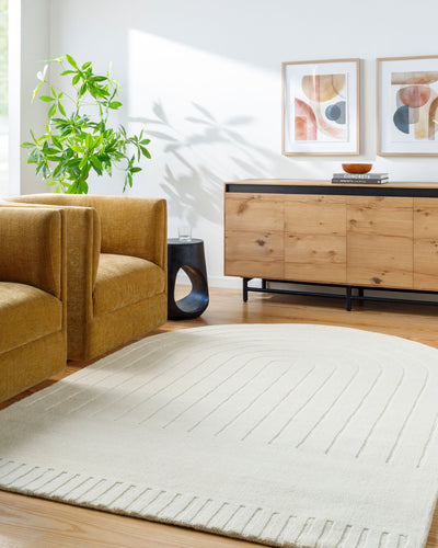 Hand-loomed Livabliss Mystique M-5496 Ivory area rug with textured arch pattern and high/low pile anchors a modern living room setting with wood furniture and a mustard chair.