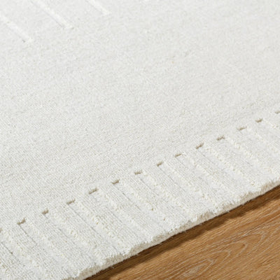 Close-up of a textured Livabliss hand-loomed Mystique M-5496 ivory wool area rug corner showing a raised pattern on light wood flooring.